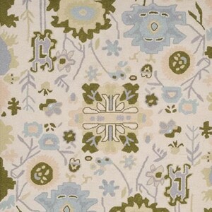 May include: A woven rug featuring an off-white background with a repeating pattern of stylized floral and botanical motifs in shades of sage green, light blue, and soft peach. The design includes symmetrical geometric shapes and organic plant forms.