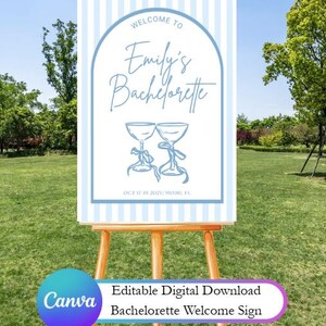 Pode incluir: Uma placa de boas-vindas para uma festa de despedida de solteira, com um fundo listrado azul claro e branco. A placa inclui o texto "Welcome to Emily's Bachelorette" e duas ta&ccedil;as de champanhe. A data e o local tamb&eacute;m s&atilde;o exibidos.