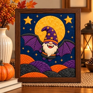 May include: A framed fabric wall art piece featuring a central gnome character with a purple star-patterned hat, white beard, and bat wings. The background displays a large yellow moon, orange and purple hills with spiderweb patterns, and yellow stars against a dark blue sky.