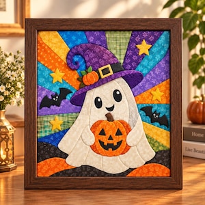 May include: A framed fabric wall art piece featuring a white ghost wearing a purple witch hat with an orange pumpkin. The ghost holds a jack-o'-lantern. The background consists of colorful fabric rays in yellow, blue, green, and purple, accented with yellow stars and black bats.