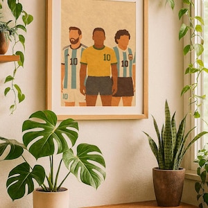 Könnte beinhalten: Gerahmter Kunstdruck mit drei Fußballspielern in ihren Trikots. Die Spieler sind in einem minimalistischen Stil dargestellt und tragen blau-weiß, gelb-grün und blau-weiß gestreifte Trikots. Der Druck wird an einer hellen Wand ausgestellt.