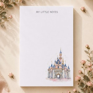 以下が含まれることがあります： 上部中央にグレーで「MY LITTLE NOTES」と印刷された長方形の白いメモ帳。右下隅には、青い屋根とピンクのアクセントが特徴的な、おとぎ話の城の繊細な水彩画イラストが描かれています。