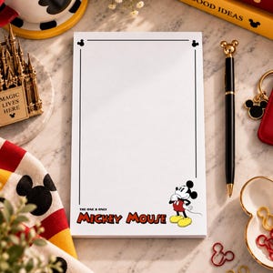 May include: A rectangular white notepad featuring a thin black border and a graphic of Mickey Mouse in the bottom right corner. The text "THE ONE & ONLY MICKEY MOUSE" is printed in black and red lettering below the character illustration.