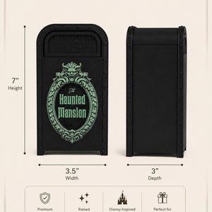 K&ouml;nnte beinhalten: Eine schwarze M&uuml;lleimer-Nachbildung mit einer gr&uuml;nen ovalen Plakette mit dem Text The Haunted Mansion und einer Wasserspeier-Figur. Der Artikel ist 17,78 cm hoch, 8,89 cm breit und 7,62 cm tief und hat eine Druckklappe an der Oberseite.