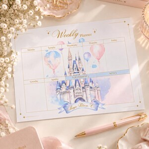 Puede incluir: Una hoja de planificador semanal blanca con una ilustración en acuarela de un castillo, globos pastel y detalles de estrellas doradas. El texto dice Weekly Planner, Top Priorities, Notes y Magic Bloom Co. La cuadrícula incluye los días.