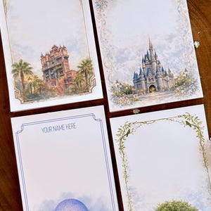 May include: Four decorative stationery cards with watercolor illustrations. One card features the Hollywood Tower Hotel, another a castle, a third has a sphere with the text "YOUR NAME HERE", and the last depicts a tree. Each card has a decorative border.