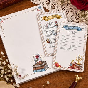Pode incluir: Um conjunto de papelaria com um bloco de notas branco grande com uma ilustração de uma rosa numa cúpula de vidro, um cartão de rastreio de livros com estantes e um cartão de crítica literária com campos para título, autor, género e nota.