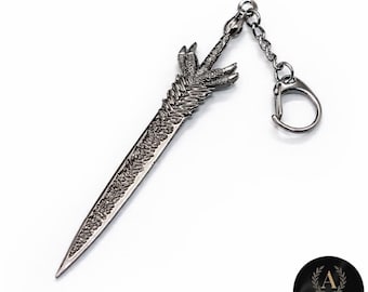 May include: A silver-colored sword keychain with intricate detailing. The hilt features a claw-like design, and the blade has etched patterns. A small chain and keyring are attached. The keychain is on a white background.