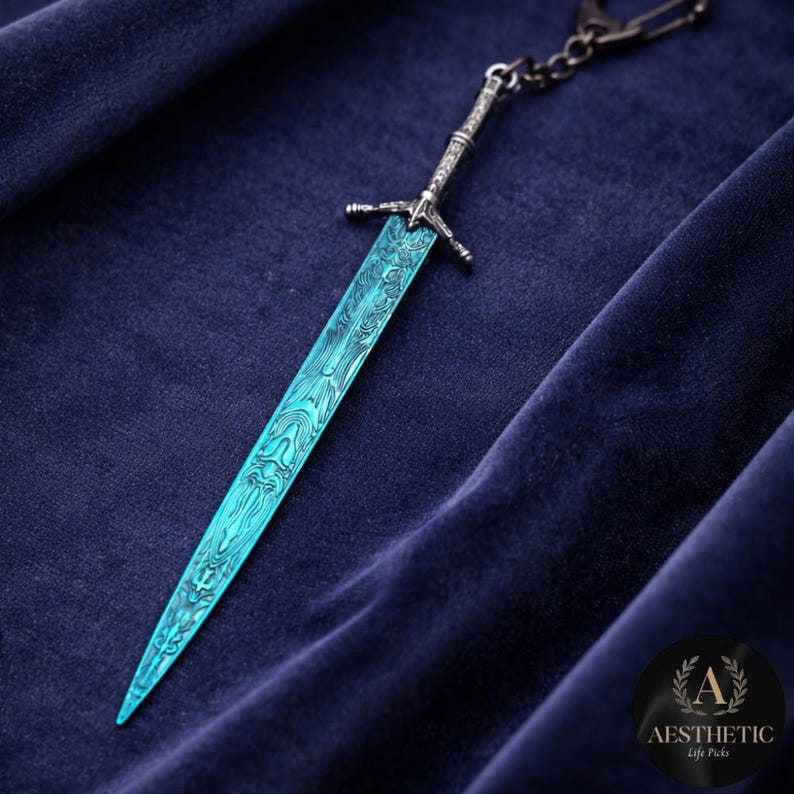 May include: A detailed, teal-colored sword keychain with an ornate handle and blade design. The blade has a unique pattern. The keychain is attached to a silver chain and is set against a dark blue background.