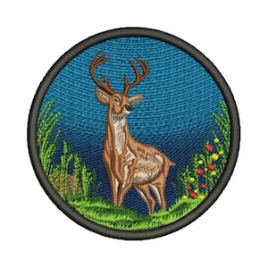 May include: Embroidered patch featuring a brown deer with large antlers, standing in a grassy field. The deer is set against a blue background with green grass and colorful flowers. The patch has a black border.
