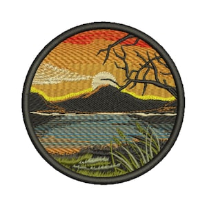 Pode incluir: Remendo bordado circular com uma cena de pôr do sol sobre um lago e montanhas. O design inclui um céu amarelo e laranja, um sol branco, montanhas escuras e um lago azul. Um galho de árvore e grama também estão incluídos. O remendo tem uma borda preta.