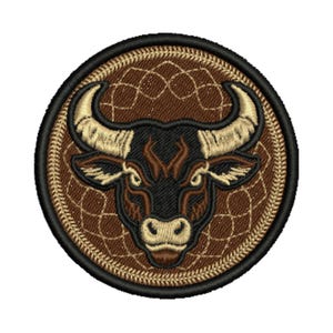 May include: Embroidered patch featuring a bull's head with large horns, in shades of brown, black, and tan. The bull is centered on a brown dreamcatcher design, all within a circular black border. The patch is likely for clothing or accessories.