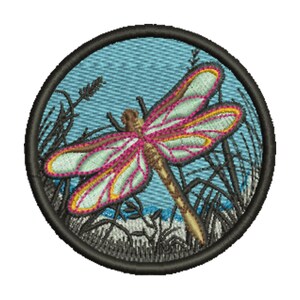 May include: Embroidered patch featuring a dragonfly with pink and yellow accents on a light blue background. The dragonfly is surrounded by embroidered reeds and grass, all within a black circular border. This patch is suitable for jackets, bags, or other fabric items.