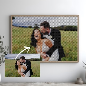 May include: A framed cross-stitch portrait of a couple laughing in a field. The cross-stitch is in black and tan thread, with a smaller photo of the couple below. The frame is light brown.