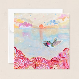 May include: A square greeting card featuring a watercolor painting of a hummingbird in flight. The artwork depicts a sunset scene with colorful clouds, stars, and red floral elements at the bottom. The card is accompanied by a white envelope.