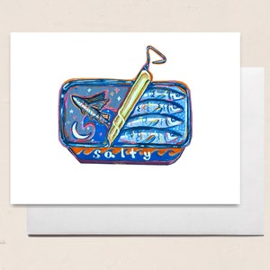 May include: A greeting card featuring a colorful illustration of a sardine can. The can is blue with the word "salty" at the bottom. Inside are three sardines and a flying fish. The can is open with a gold pull tab. The card is on a white background.