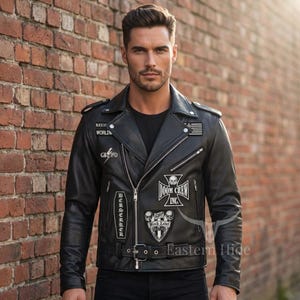May include: Black leather motorcycle jacket with multiple patches, including "DOOM CREW INC." and "BLACK LABEL WORLD". The jacket features a zipper closure, a belt at the waist, and a classic biker style. The jacket is worn over a black shirt.