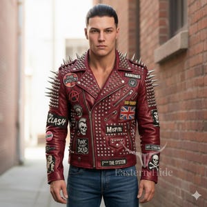 Könnte beinhalten: Burgunderfarbene Lederjacke mit silbernen Stacheln an Schultern und Kragen. Die Jacke hat Aufnäher mit Bandnamen und Punkrock-Symbolen, darunter "The Clash" und "Ramones". Die Jacke ist mit silbernen Nieten besetzt und hat einen Reißverschluss.
