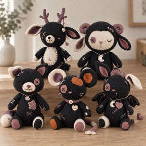 Puede incluir: Una colección de cinco peluches tejidos con hilo negro y crema con detalles cosidos. El grupo incluye un ciervo con astas, un carnero con cuernos, un gato, un ratón con un parche de calabaza y una criatura alada con un corazón.