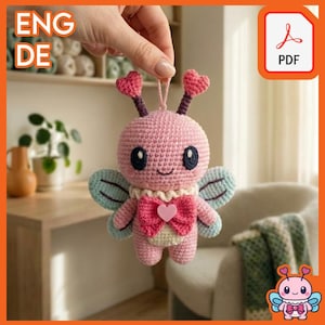 May include: A handmade pink crochet butterfly with heart-shaped antennae and a pink bow. The butterfly has blue and green wings and large, dark eyes. The image also includes a PDF icon in the upper right corner.