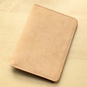 May include: A light brown leather notebook cover with white stitching around the edges.