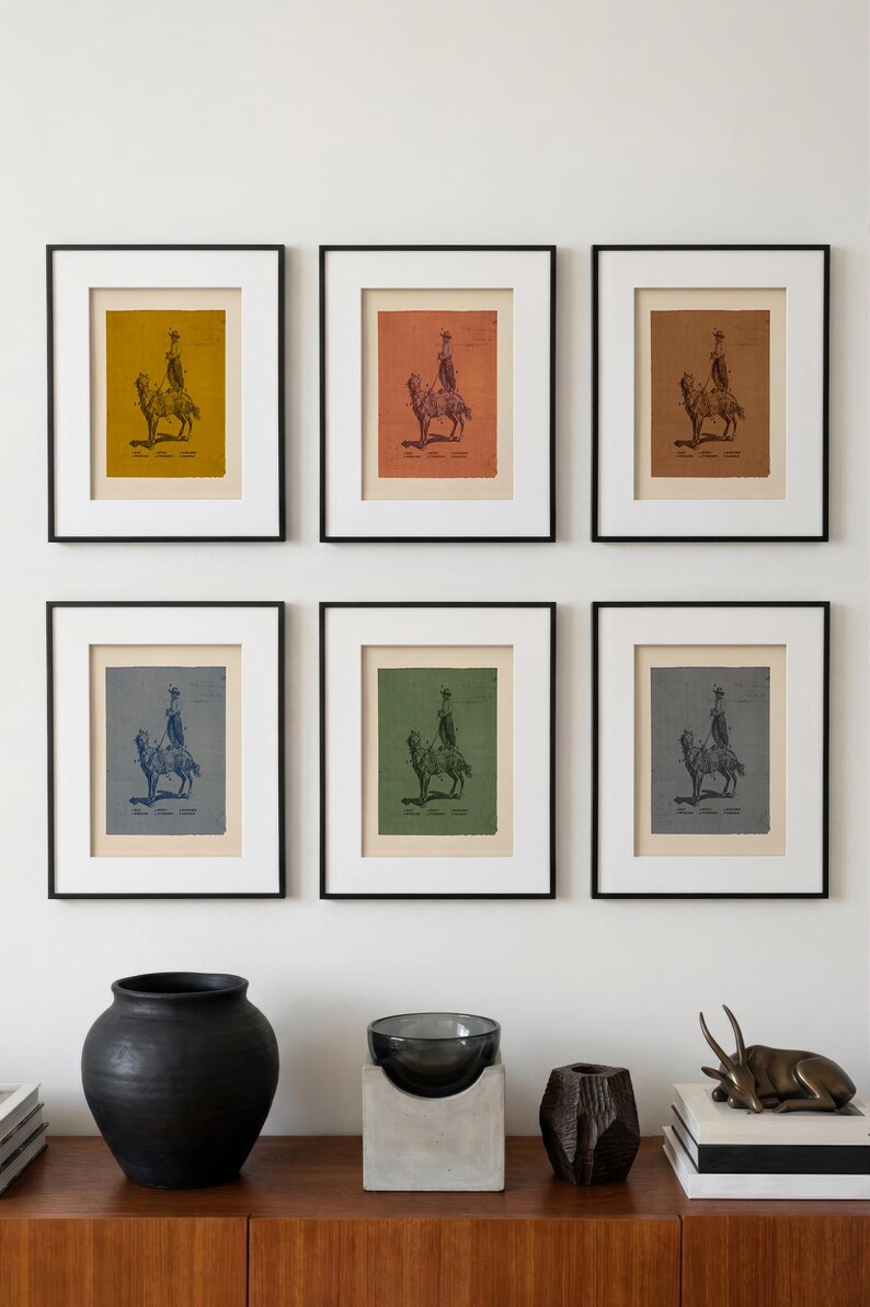 May include: Six framed prints arranged in two rows, each featuring a dark illustration of a person riding a camel. The prints have varied background colours including mustard, terracotta, brown, blue, green, and grey, all within black frames.