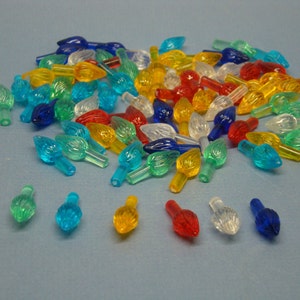 May include: A large assortment of colorful plastic Christmas light bulb tips. The tips are in various colors, including red, yellow, blue, green, and clear. The tips are shaped like flames.