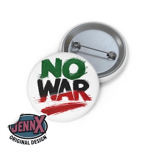 Puede incluir: Una chapa redonda con un alfiler en la parte posterior que muestra el texto NO WAR en estilo de pincelada. La palabra NO es verde y la palabra WAR es negra y roja. La chapa tiene un fondo blanco y un mecanismo de alfiler metálico visible.
