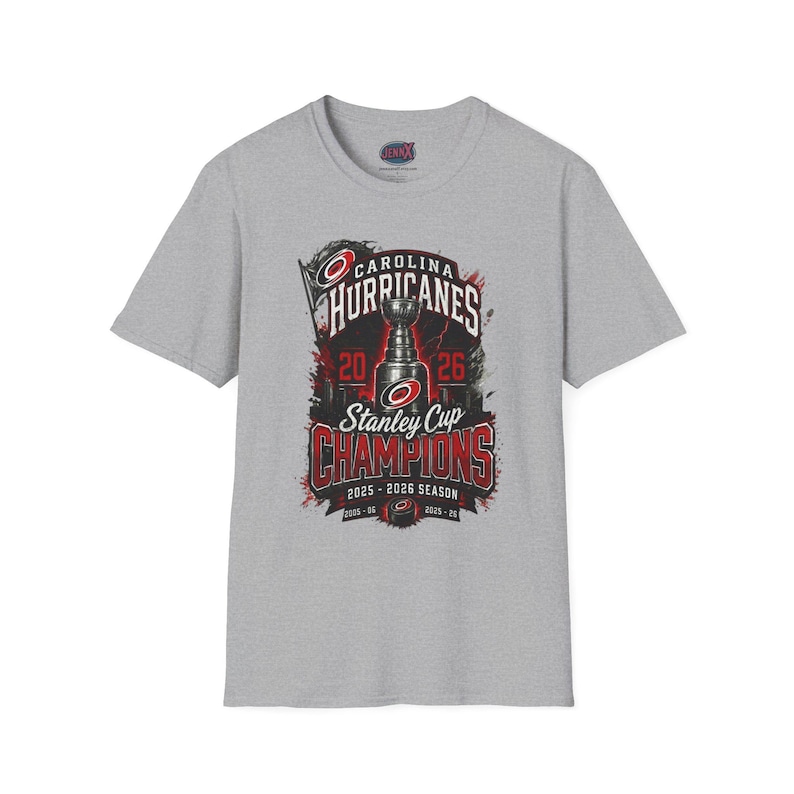May include: A heather gray short-sleeve t-shirt featuring a graphic of the Stanley Cup with the text Carolina Hurricanes Stanley Cup Champions 2025-2026 Season. The design includes red and black accents with the team logo and years 2006 and 2025.