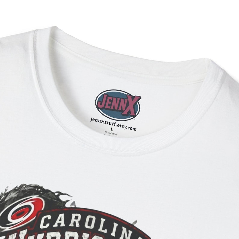 May include: A white t-shirt featuring a crew neckline and a printed inner label that reads JENNX, jennxstuff.etsy.com, L, and 100% Cotton. The lower portion of the shirt displays a partial graphic with the text CAROLINA in bold white letters.