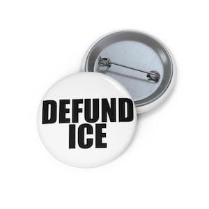 Pode incluir: Um botton redondo com alfinete apresentando um fundo branco com o texto preto em negrito DEFUND ICE impresso no centro. A parte de trás do botton é feita de metal prateado e inclui um mecanismo de alfinete horizontal para fixação no tecido.