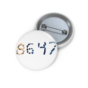 Peut inclure: Deux badges ronds blancs. L'un des badges porte le numéro "9647" dans un mélange de couleurs marron et bleu. L'autre badge est partiellement visible, montrant l'attache métallique. Les badges sont probablement utilisés comme accessoires ou pour la décoration.
