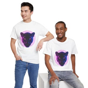 May include: Two people wearing white t-shirts featuring a panther head design. The panther is depicted in shades of purple and blue, encircled by a pink and purple ring. The shirts are paired with blue and gray jeans.