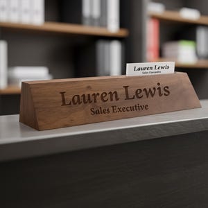 Puede incluir: Un letrero de escritorio de madera con el nombre "Lauren Lewis" y el t&iacute;tulo "Sales Executive" grabados. Una tarjeta de visita con el mismo nombre y t&iacute;tulo est&aacute; en una ranura. El letrero es de madera oscura.