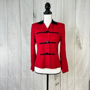 May include: A red blazer with black trim and buttons. The blazer has a collar and long sleeves.