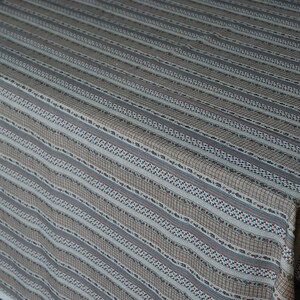 May include: A white tablecloth with brown, blue, and red stripes. The tablecloth has a woven texture and a subtle pattern.