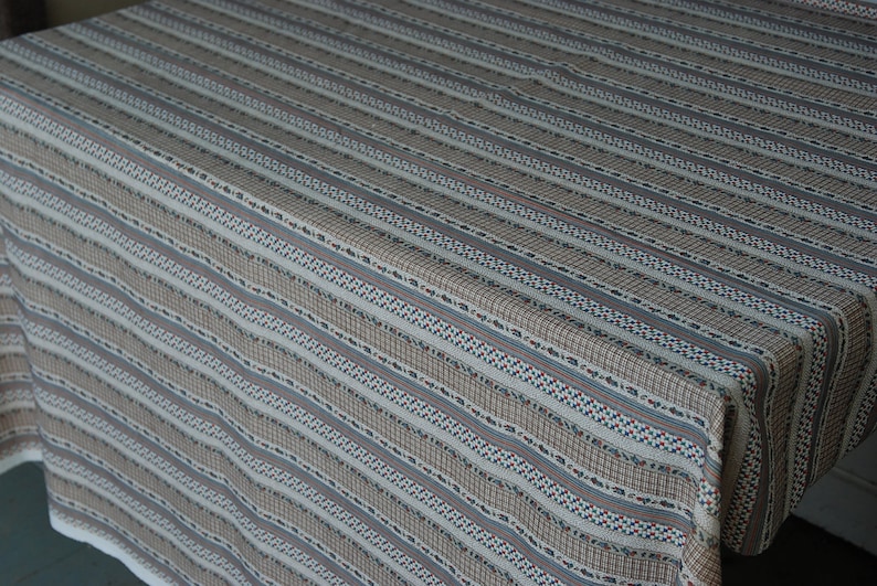 May include: A white tablecloth with brown, blue, and red stripes. The tablecloth has a woven texture and a subtle pattern.