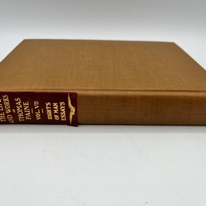 Könnte beinhalten: Ein braunes Buch mit rotem Rücken. Der Rücken hat goldene Schrift, die "The Life and Works of Thomas Paine Vol. VII - Rights of Man Essays" lautet.