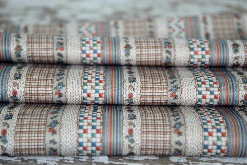 May include: Close-up of a stack of fabric with a brown, white, blue, and red striped pattern. The fabric has a small floral design.