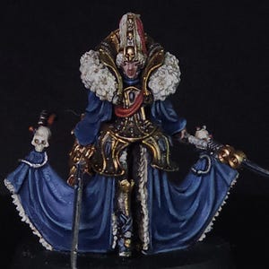 May include: Miniature figure of a character in a blue and gold outfit with a white fur collar. The figure is holding a sword and a staff with a skull on top. The figure is standing on a black base.