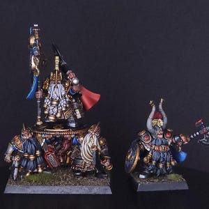 Puede incluir: Figuras de fantasía en miniatura de enanos, pintadas con armaduras y armas detalladas. Una figura sostiene una bandera, otras empuñan hachas y escudos. Las figuras están sobre pequeñas bases, con un fondo oscuro.