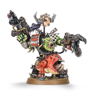 May include: A miniature Ork warboss figure, green-skinned with large teeth, wielding a gun and a mechanical claw. The figure is mounted on a red creature and stands on a brown base. The figure has a checkered flag and a metal weapon.
