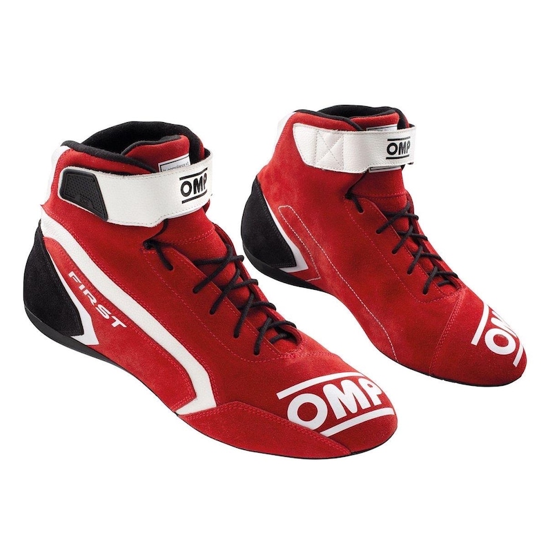 May include: Pair of red racing boots with white detailing and black laces. The high-top boots feature a white ankle strap and the word "FIRST" on the side. The brand name "OMP" is displayed on the boots.