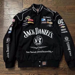 Puede incluir: Chaqueta de carreras negra con detalles blancos y parches de patrocinadores. La chaqueta presenta el logotipo de Jack Daniel's en la parte delantera y en las mangas, junto con el texto "Pace Yourself. Drink Responsibly."