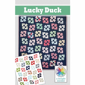 Peut inclure: Un modèle de courtepointe appelé "Lucky Duck" par a bright corner. Le motif présente un fond bleu avec des carrés colorés et une variété d'imprimés floraux.