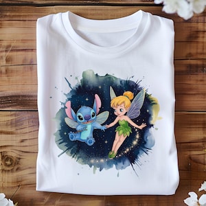 May include: White t-shirt featuring a watercolor design of Stitch and Tinkerbell. Stitch is blue with fairy wings, and Tinkerbell is in a green dress with fairy wings. The background is a dark blue and green watercolor splash.