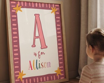 Könnte beinhalten: Ein gerahmter rechteckiger Wandkunstdruck mit einem großen rosa Buchstaben A, dem Text is for und dem Namen Allison in bunten Buchstaben. Der Druck hat einen dunkelrosa Rand mit Strichen und vier gelben Sternen in den Ecken.