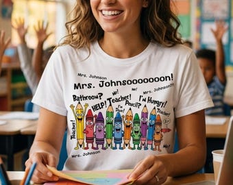 Könnte beinhalten: Ein weißes T-Shirt mit einer bunten Grafik aus Zeichentrick-Bleistiften und Buntstiften mit Gesichtern. Der Text lautet: Mrs. Johnson, Mrs. Johnsooooooon!, Bathroom?, Me!, Help! Teacher!, I'm Hungry!, Pencil?, Teacher!, I'm Done!, und Me!.