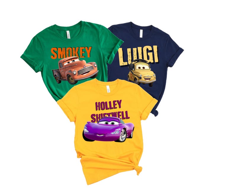 May include: Three short-sleeved t-shirts in green, navy blue, and yellow. Each shirt features a cartoon car graphic and a name: "Smokey", "Luigi", and "Holley Shiftwell". The shirts are made of a soft material.