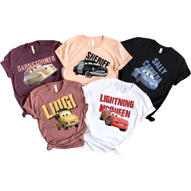 May include: Five short-sleeved t-shirts featuring characters from the movie Cars. The shirts are in various colors, including maroon, peach, and white. Each shirt has a different character graphic and name, such as "Barnstormer" and "Lightning McQueen."